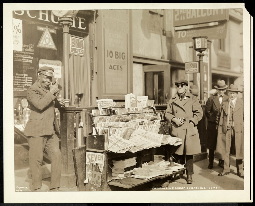 Revendedor cego de notícias, John Lanz, em seu estande no canto nordeste da 7th Avenue e 47th Street, Nova York, 1926 (impressão em gelatina de prata) de Byron Company