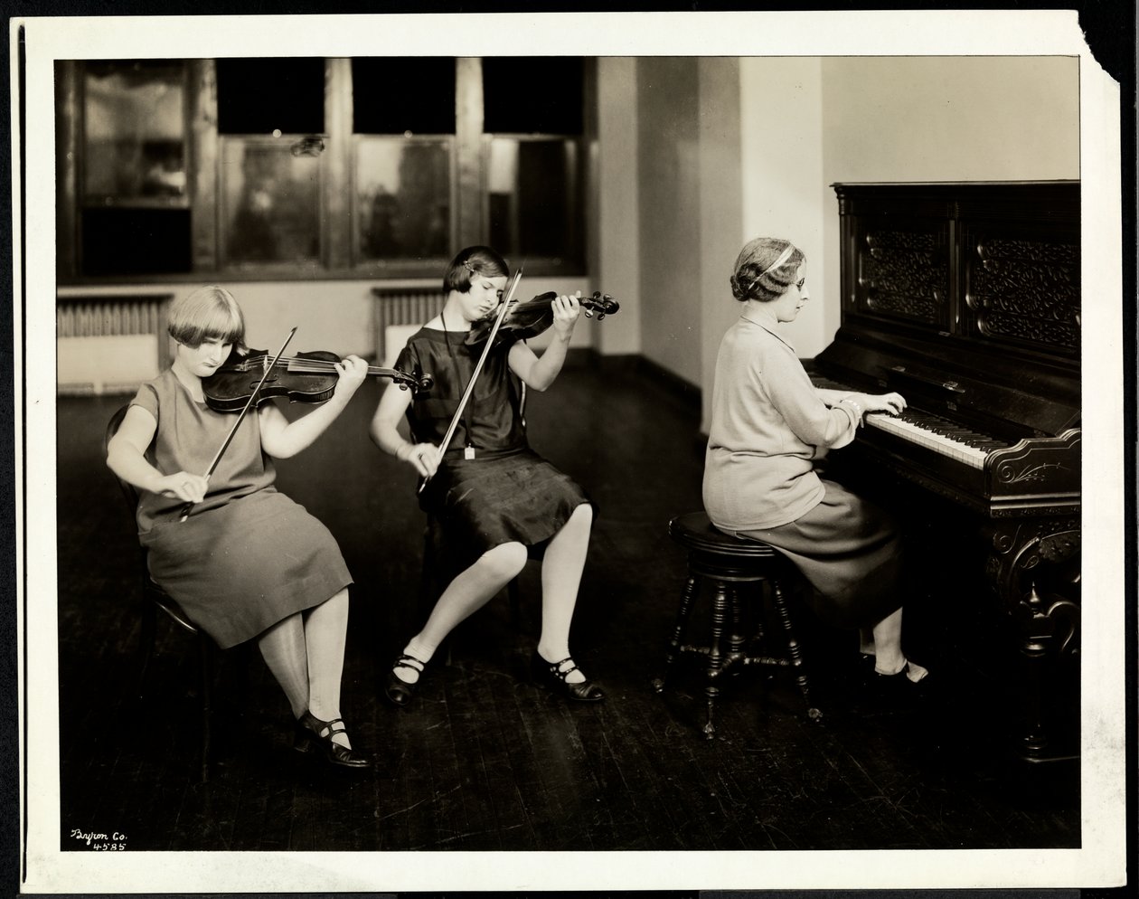 Grupo de três jovens cegas, uma ao piano, duas tocando violino, na Associação Nova York para Cegos, 111 East 59th Street, Nova York, 1926 (impressão em gelatina de prata) de Byron Company