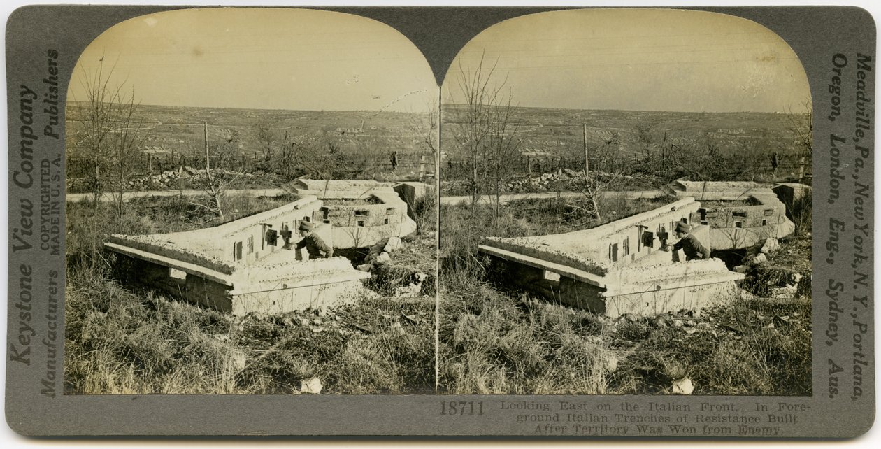 Estéreo horizontal, do sepia que mostra um homem uniformizado que está atrás de um grupo de trincheiras concretas em um campo aberto. Keystone Stereograph number 18711. O título indica de Keystone View Company