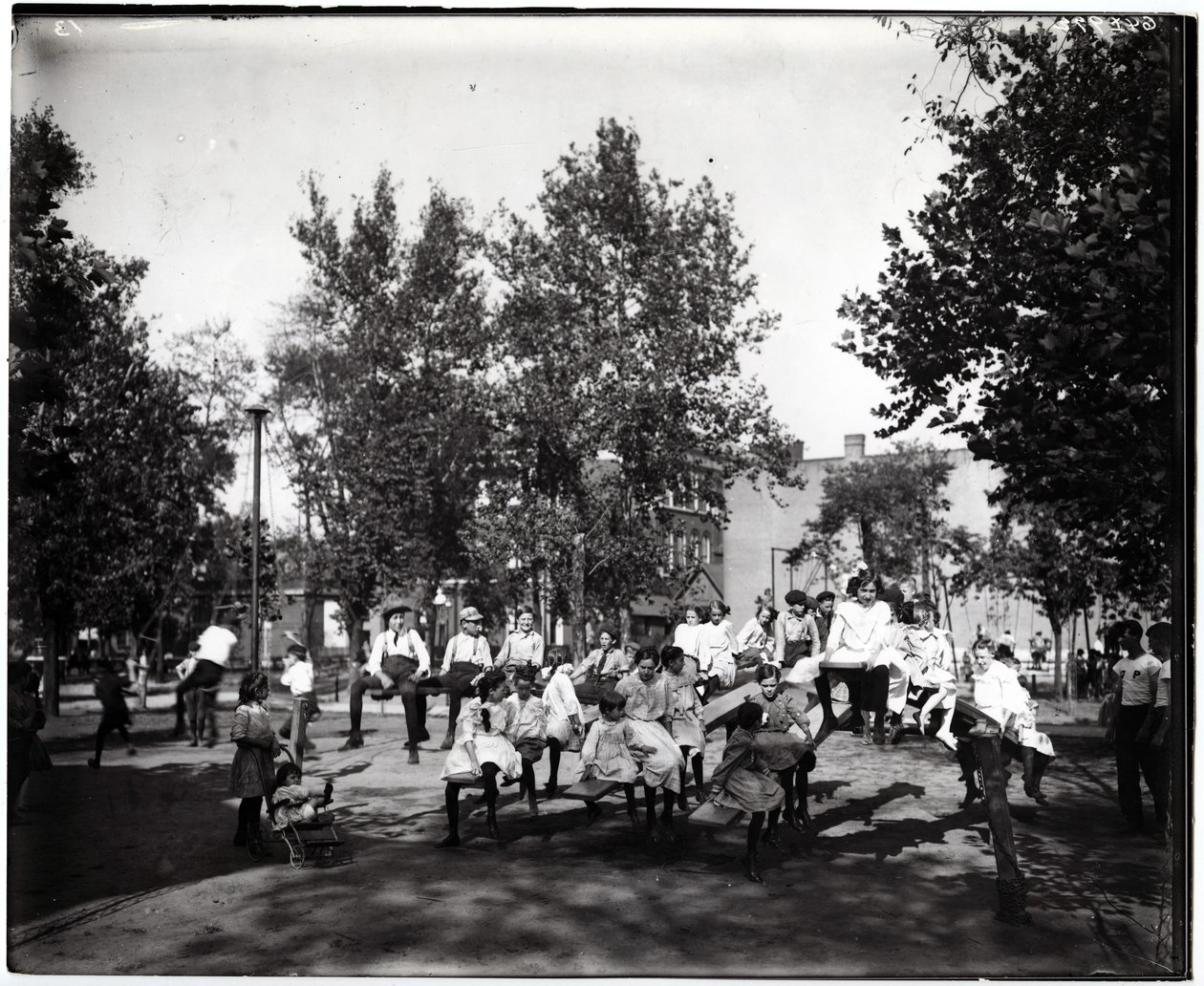 Fotografia horizontal, preto e branco, mostrando crianças brincando em gangorra em um parque não identificado de Unknown