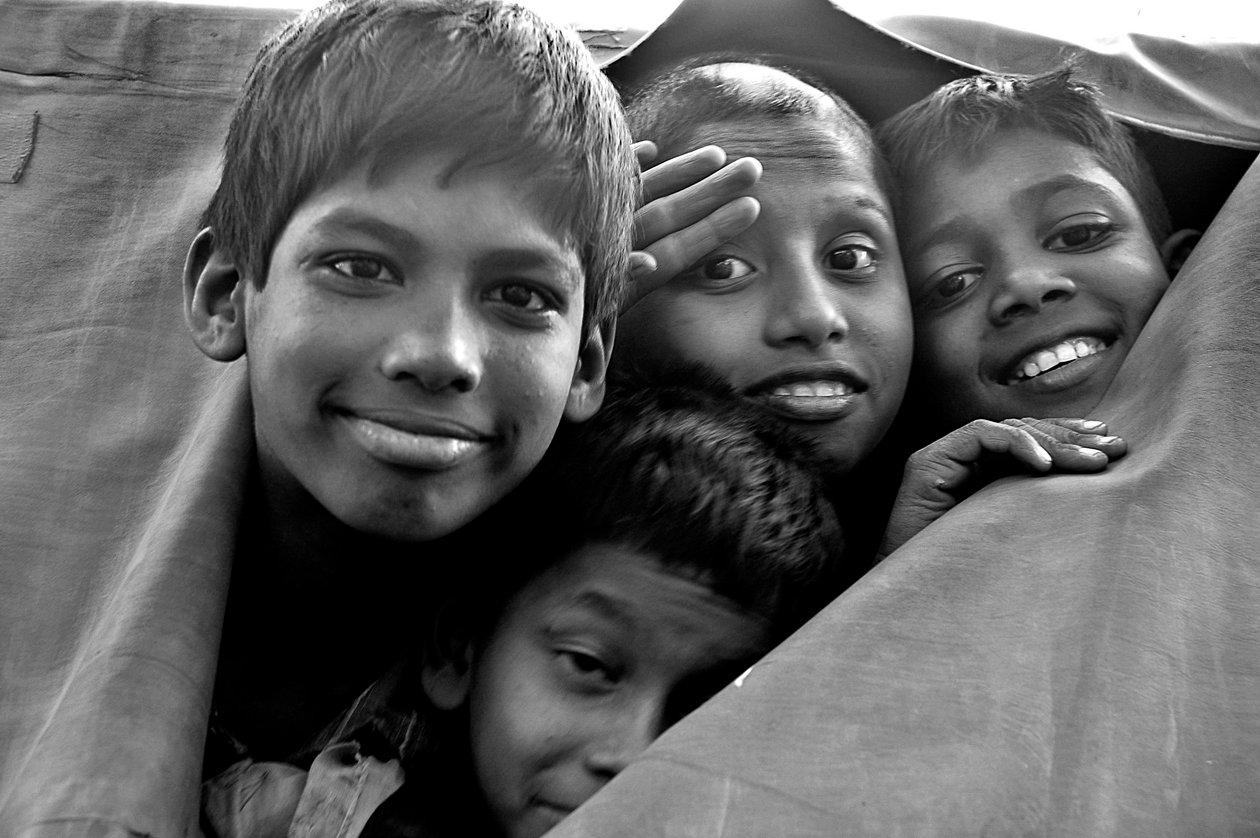 Crianças desamparadas olham através de uma lona rasgada de uma van da polícia na cidade de Dhaka, Bangladesh. 26 de novembro de 2006. de Unknown