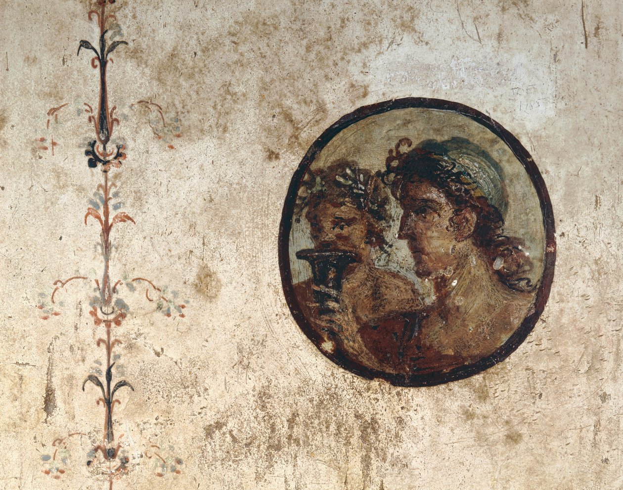 Interior de um quarto com afrescos de parede do período romano, estilo III, na casa de Corieo Tiburtino em Pompéia: parte de uma videira e um tondo com duas cabeças masculinas de Unknown