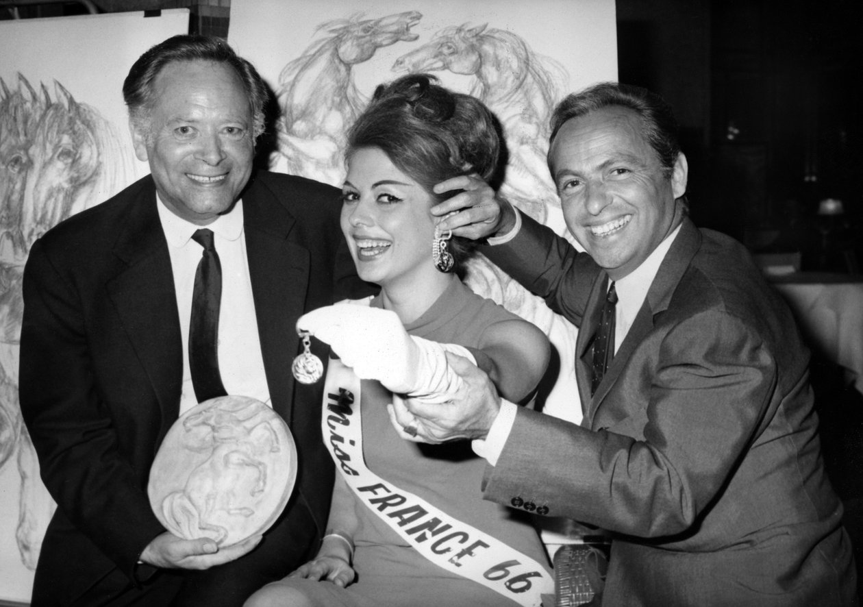 Rene Bollinger (Esquerda) E Guy Lux Entourent Monique Boucher “Miss França” A Quem Eles Apenas Entregam Em Um Chaveiro “Talisman Du Turfiste” Durante A Abertura Da Tela De Bollingers Em 12 De Julho De 1966 de Unknown