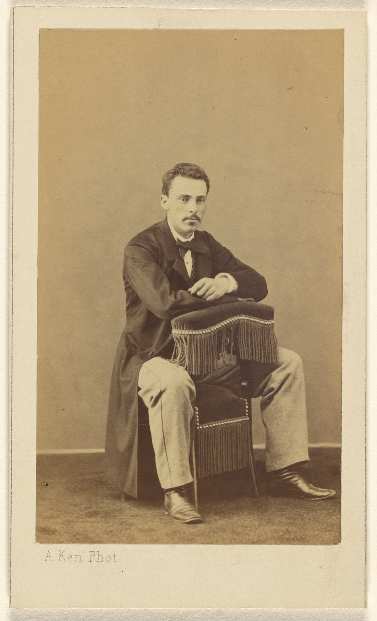 [Homem de bigode, sentado, com a frente para trás da cadeira com franjas]. de Alexandre Ken