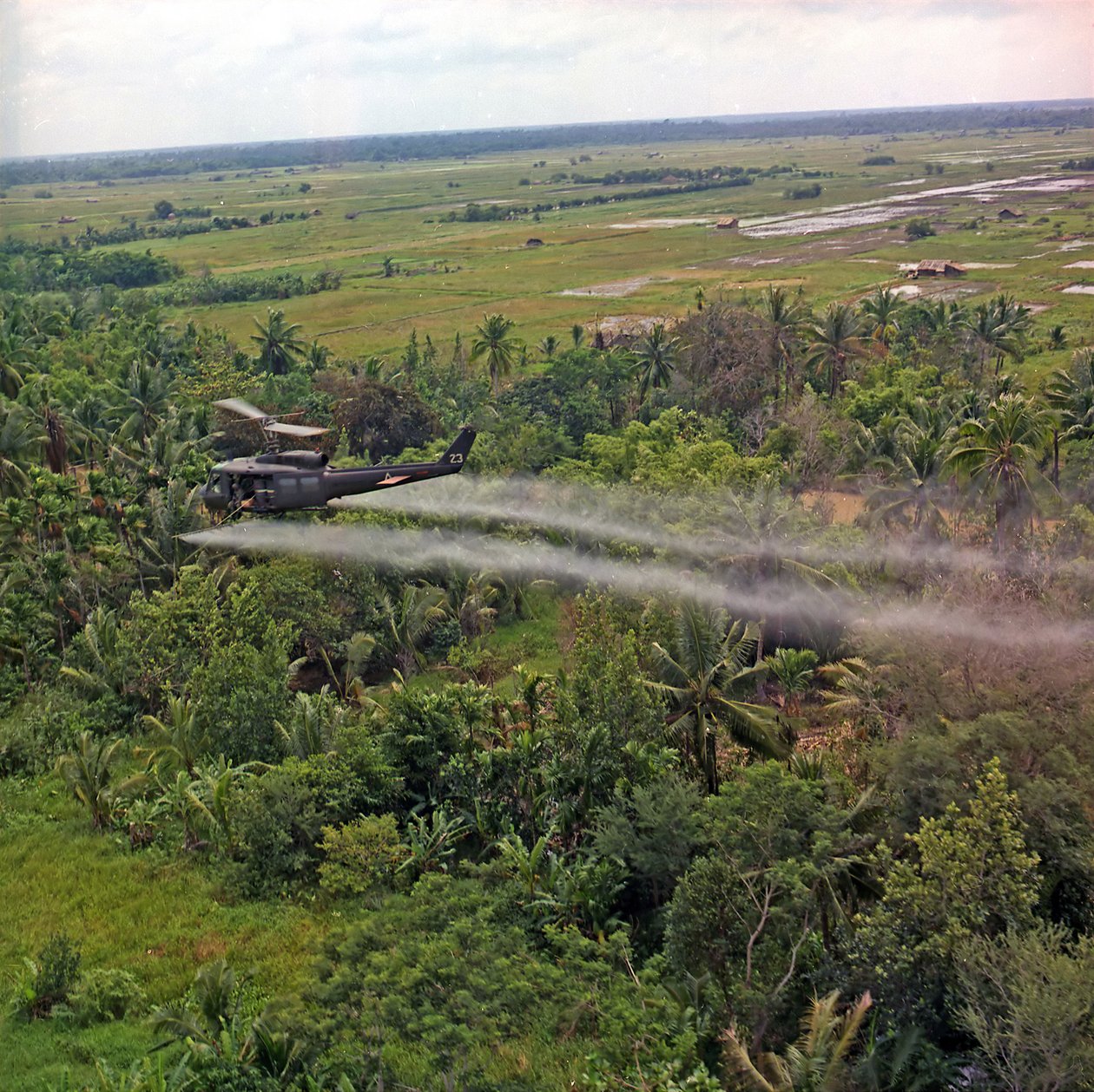 Um helicóptero UH-1D da 336th Aviation Company pulveriza um agente de desfolhação em uma densa área de selva no delta do Mekong, em 26 de julho de 1969 de American Photographer