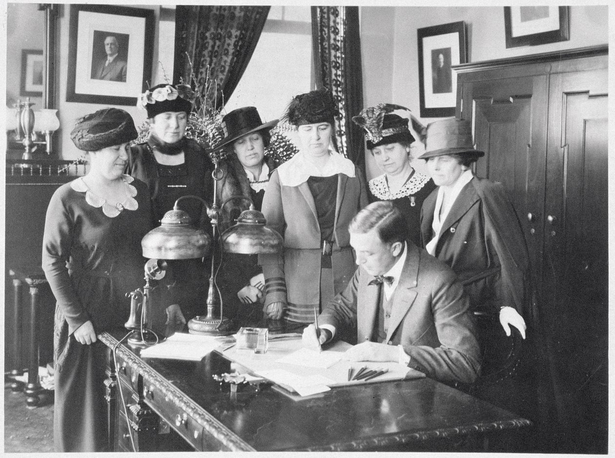 Governador Carl Elias Milliken assinando a Lei do Sufrágio em seis mulheres, 1917 de American Photographer