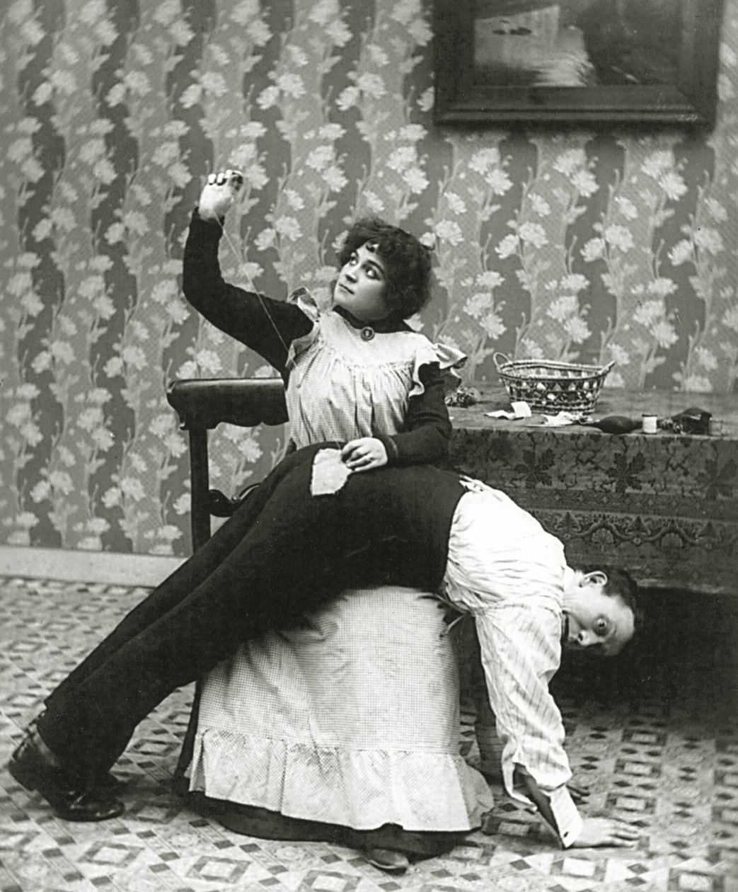 Mulher costurando uma lágrima em uma calça do homem, c.1895 de American Photographer