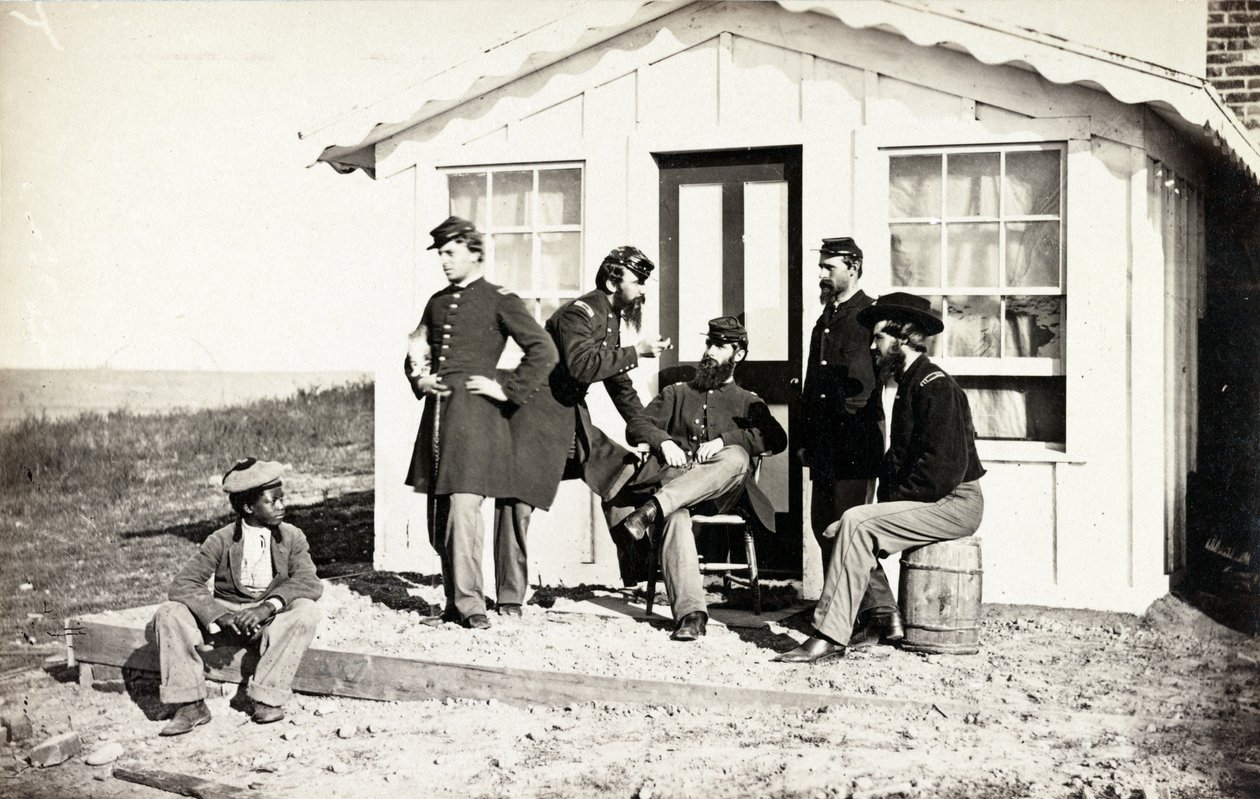 Cinco soldados da Guerra Civil se reuniram na varanda suja fora de casa, juventude afro-americana sentada perto deles, 1861-65 de American Photographer