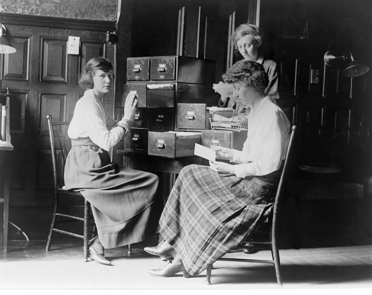 Três mulheres trabalham nos arquivos do índice de cartões na sede do National Womans Party, em Washington DC, pub. c.1920 de American Photographer
