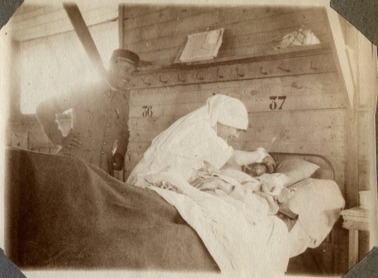 Primeira Guerra Mundial 1914-1918: enfermeira de blusa rapando um soldado (as feridas de guerra francesas jazem numa cama), em Couville, Manche, Baixa Normandia (Baixa Normandia), França. Fotografia anônima de julho de 1917. Coleção particular, Stella. de Anonymous Anonymous