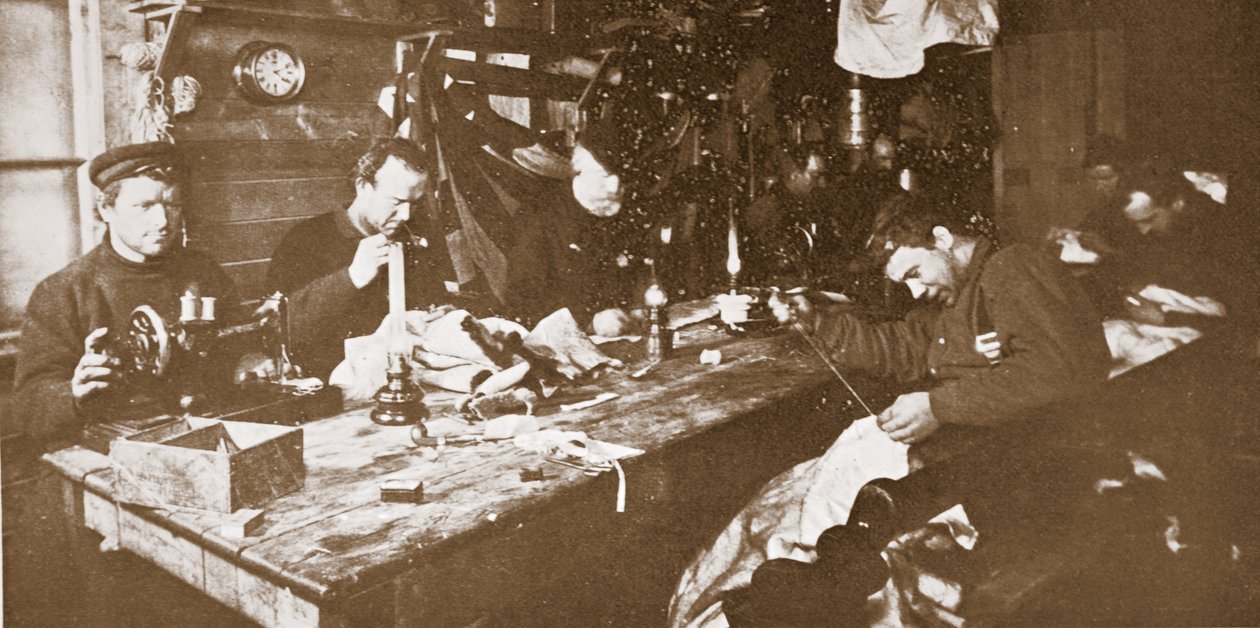 Na cabana durante o meio do Inverno, os homens que se dedicavam à costura de peles para vestuário a ser utilizado em trenós primaveris, pub. Londres 1907 (foto a p/b) de Anthony Fiala