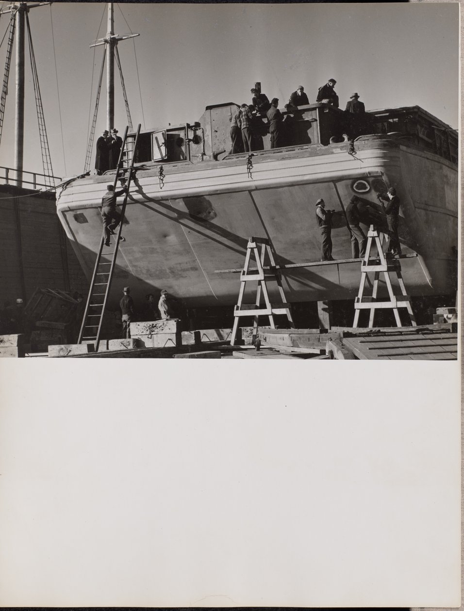 [Um grupo de homens trabalha num barco atracado]. de Arnold Eagle
