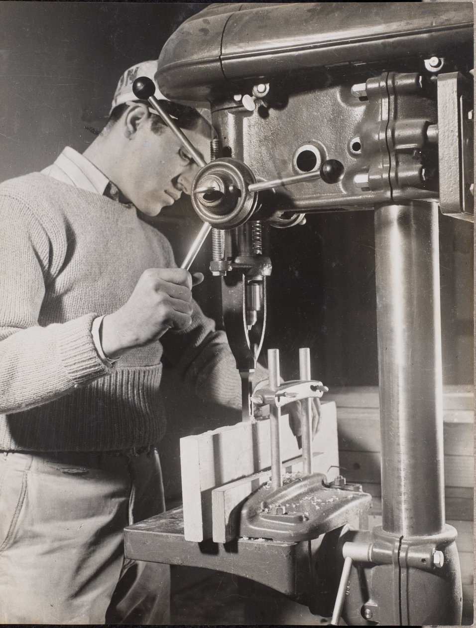 [Homem utiliza uma máquina para fazer furos em dois blocos de madeira]. de Arnold Eagle