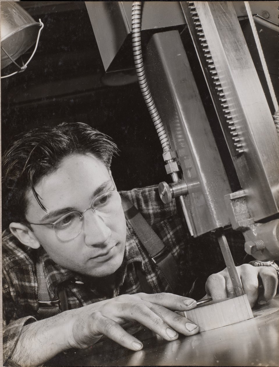 [Homem de óculos trabalha atentamente com um ficheiro industrial] de Arnold Eagle