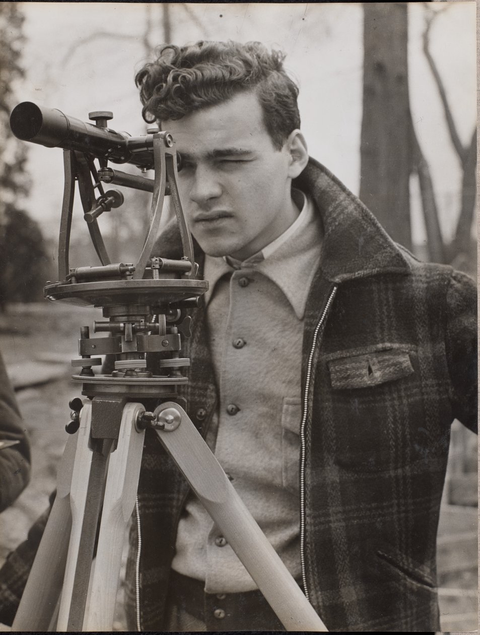 [Jovem espreita através de uma ferramenta de topógrafo]. de Arnold Eagle