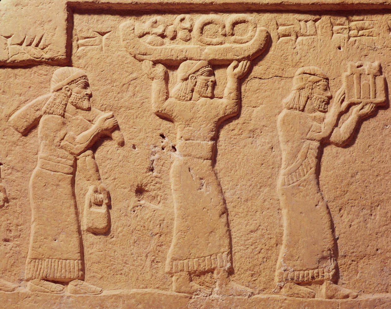 Relevo retratando porteiros carregados de presentes de Assyrian