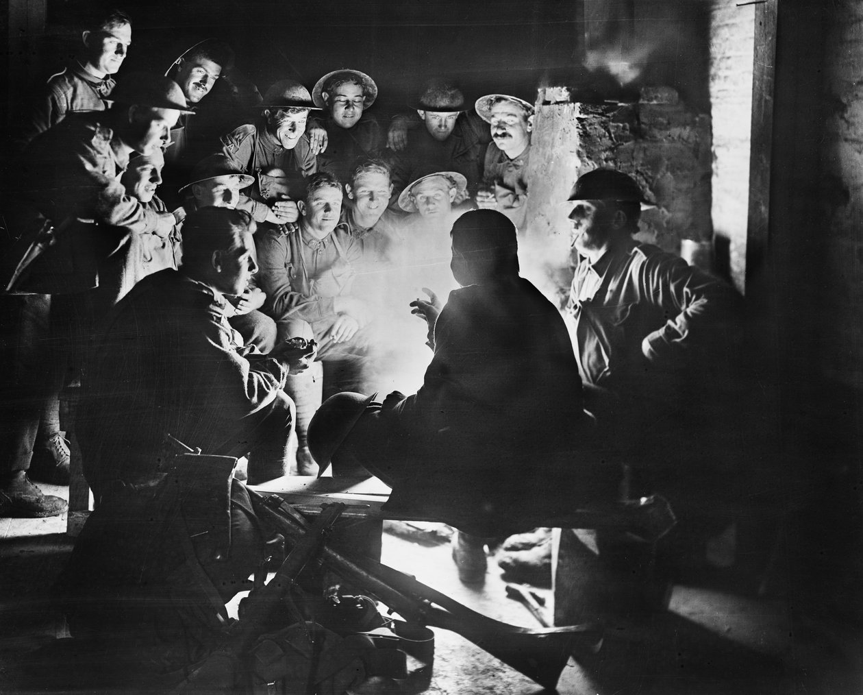 Membros da 1ª Bateria de Argamassa Trincheira Ligeira Australiana, 1ª Divisão Australiana ouvindo as últimas de um de seus companheiros em torno de um incêndio em um abrigo em Ypres, 28 de outubro de 1917 (bw pho de Australian Photographer