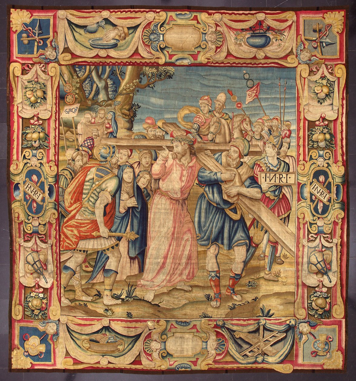 Cristo e Simão de Cirene (o Cireneu). (Quinta paragem da Via Sacra (carregando a cruz). Um pedaço da cruz tem a inscrição I.N.R.I. (INRI). Tapeçaria fabricada nas manufacturas de Bruxelas. Século XVI Genes, Musei di Strada Nuova de Belgian School