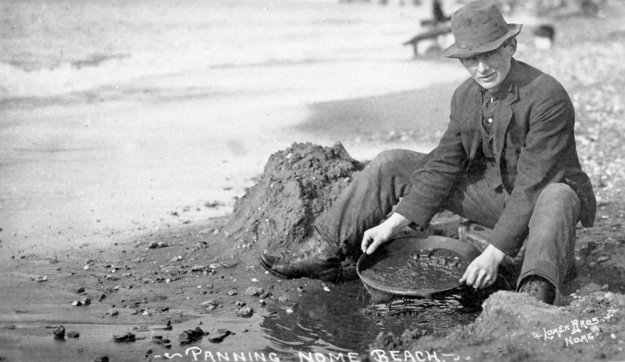 Homem Panning Gold on Beach, Nome, Alasca, c.1910 (foto a p/b) de Brothers Lomen