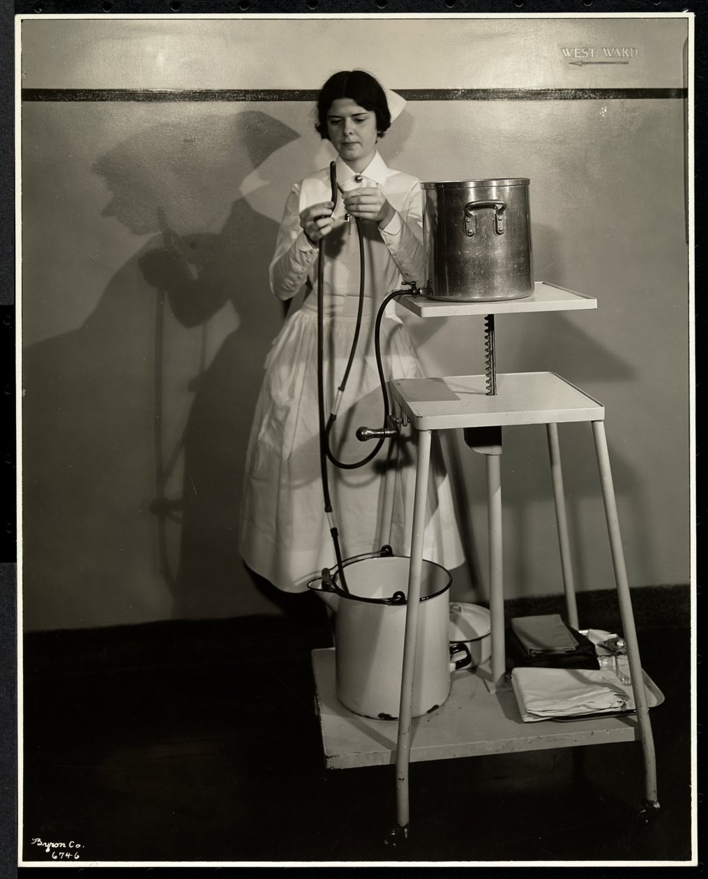 Uma enfermeira demonstrando um aparelho especial com tubos e suprimentos e recusando baldes no Sloan Maternity Hospital, Broadway e 168th Street, Nova York, 1932 (impressão de gelatina de prata) de Byron Company