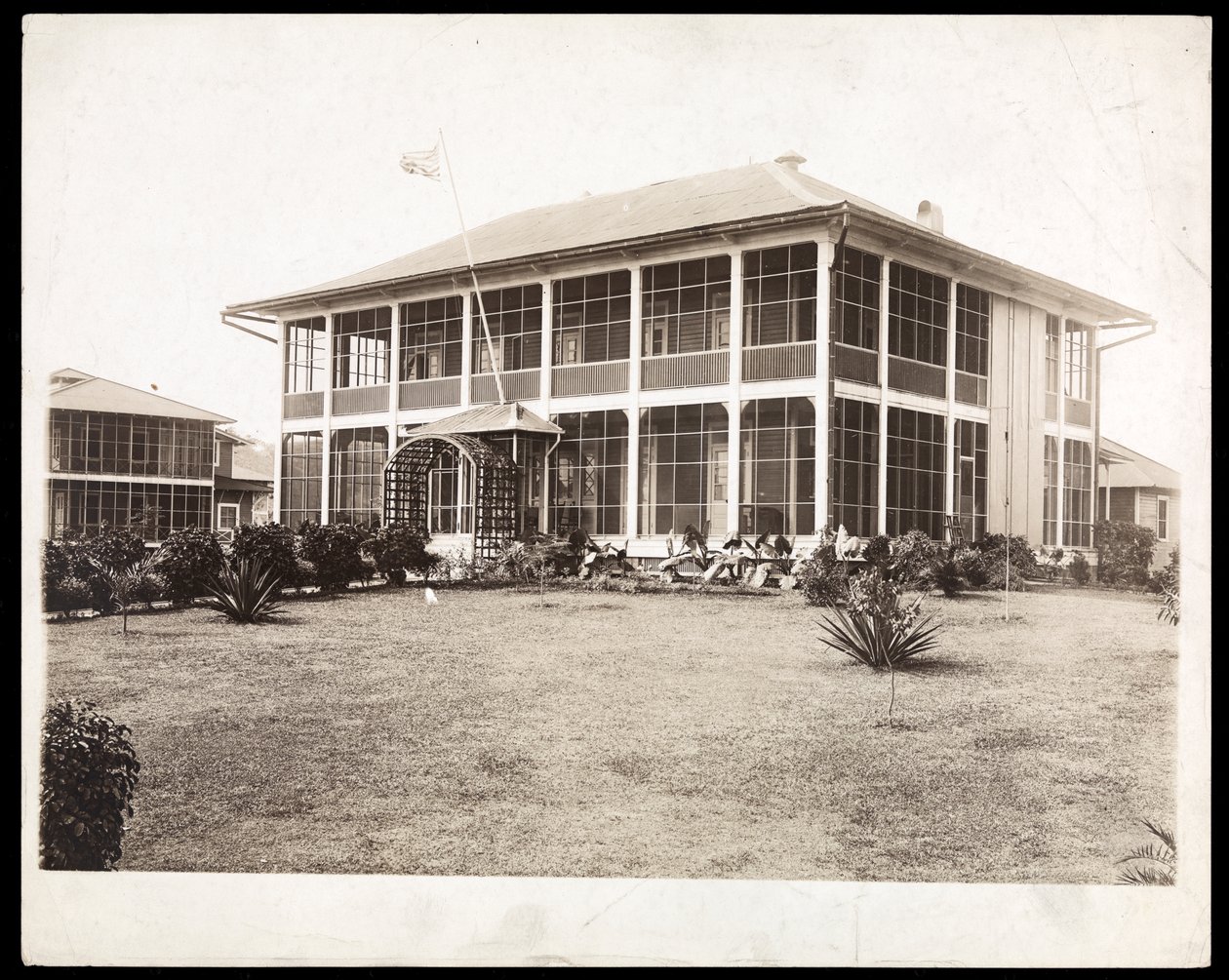 Uma casa de dois andares cercada por varandas, com uma bandeira americana voando; no Panamá durante a construção do canal, 1912 (impressão de gelatina de prata) de Byron Company