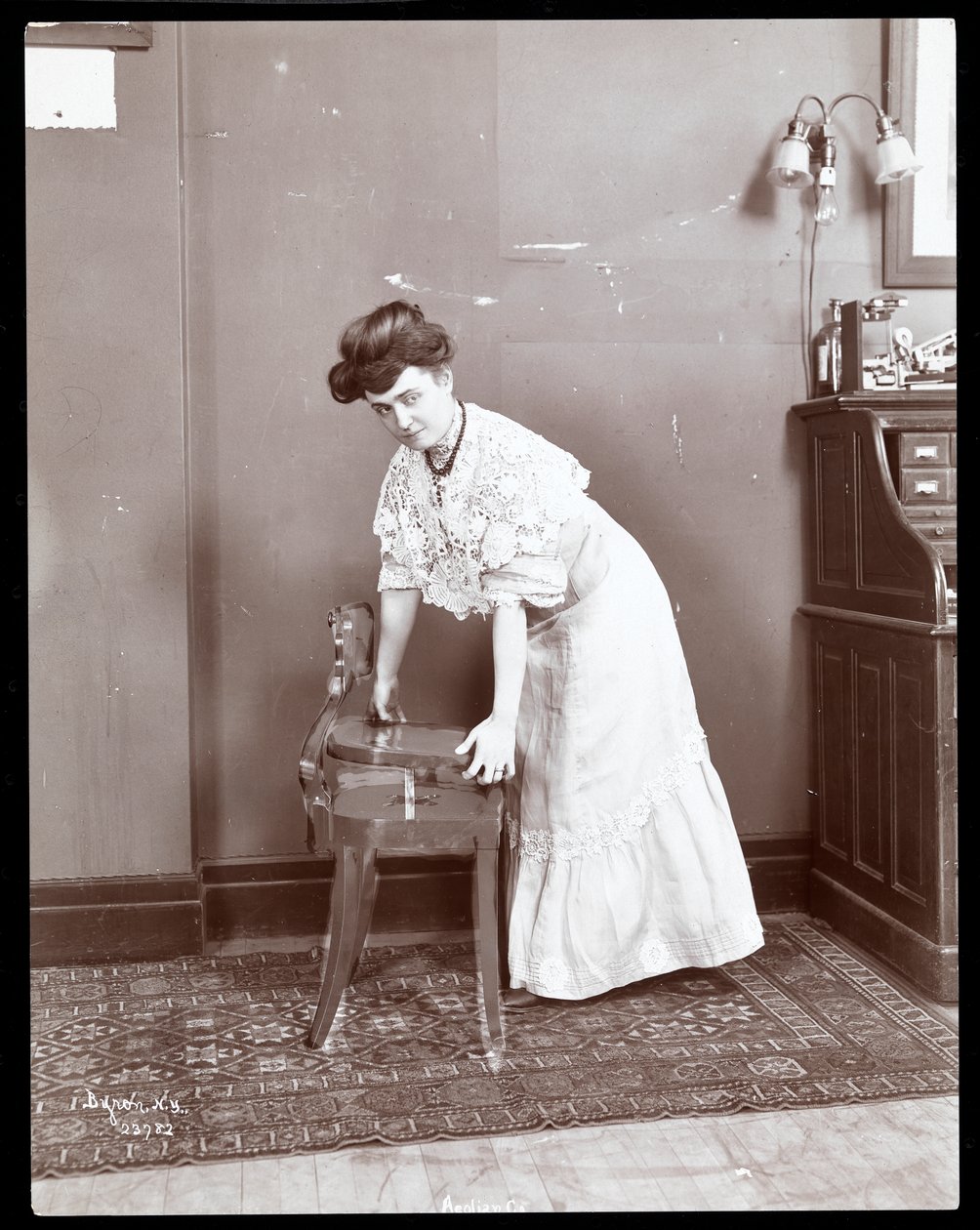 Uma mulher demonstrando uma cadeira especial na Aeolian Co., Nova York, 1906 ou 1907 (impressão de gelatina de prata) de Byron Company