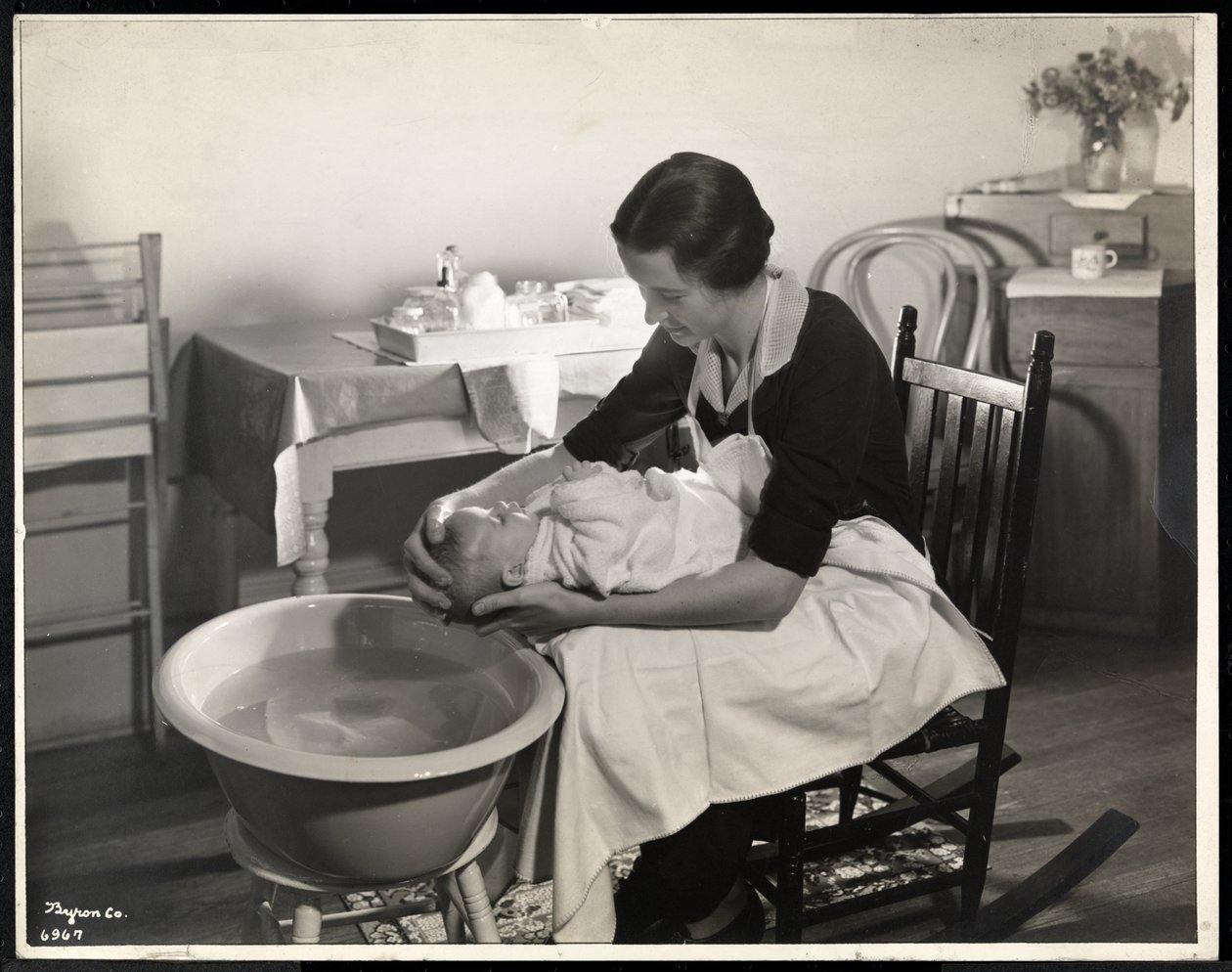 Uma mulher lavando a cabeça de um bebê na Maternity Center Association em 211 East 57th Street, Nova York, 1934 (impressão em gelatina de prata) de Byron Company