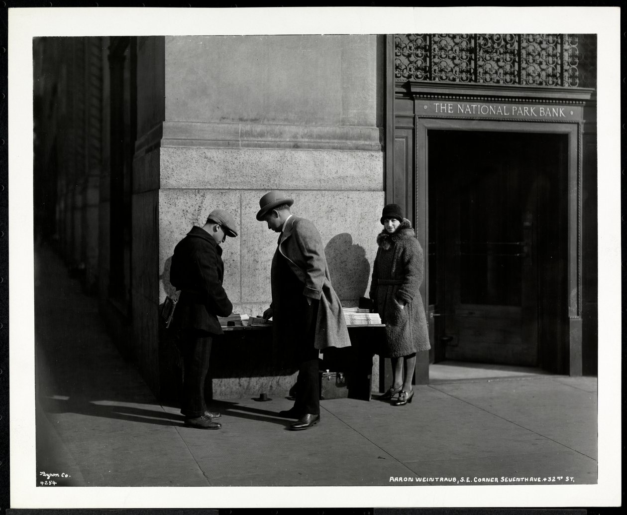 Revendedor cego de notícias, Aaron Weintraub, em seu estande no canto sudeste da 7th Avenue e 32nd Street, Nova York, 1930 (impressão em gelatina de prata) de Byron Company