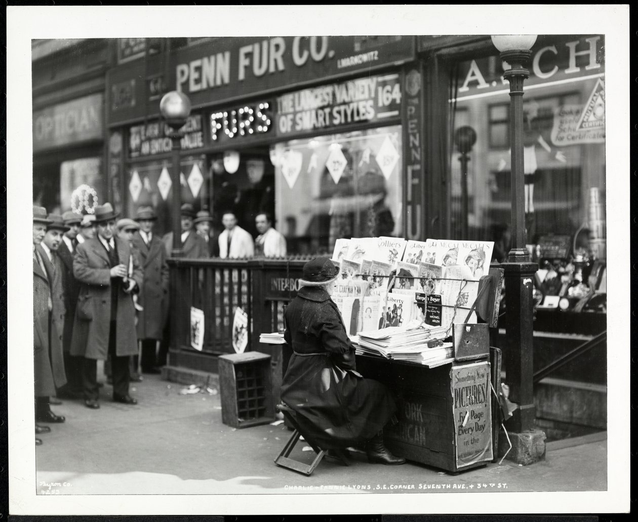 Revendedor cego de notícias, Aaron Weintraub, em seu estande no canto sudeste da 7th Avenue e 32nd Street, Nova York, 1926 (impressão em gelatina de prata) de Byron Company
