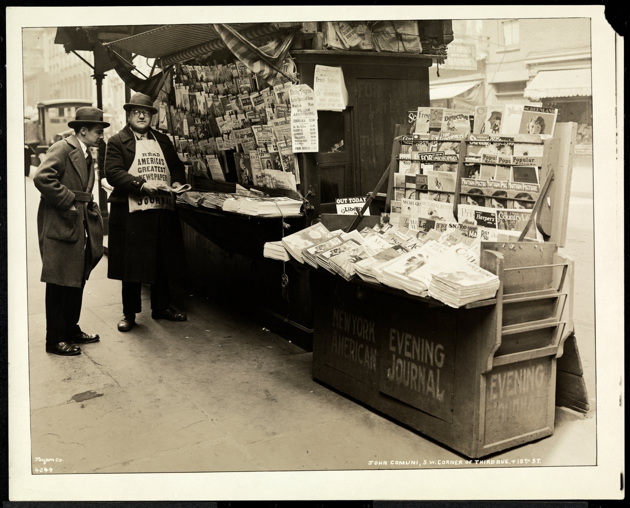Negociador de notícias às cegas, John Comuni, em seu estande na 3rd Avenue e na 18th Street, Nova York, 1926 (impressão em gelatina de prata) de Byron Company