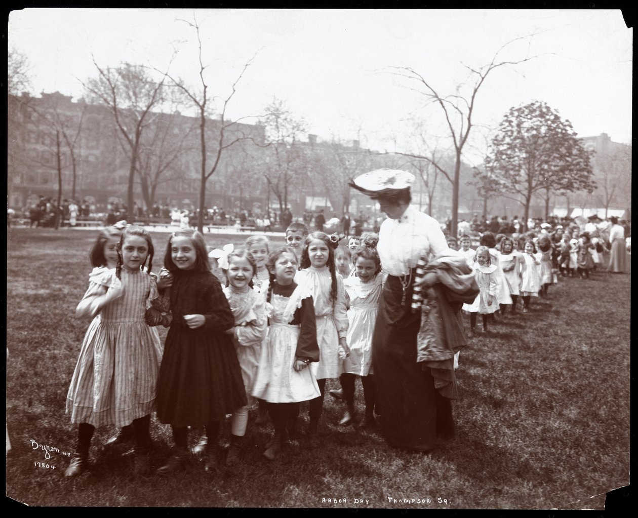Crianças em uma longa fila sendo liderada por uma mulher no Dia da Árvore no Tompkins Square Park, Nova York, 1904 (impressão em gelatina de prata) de Byron Company