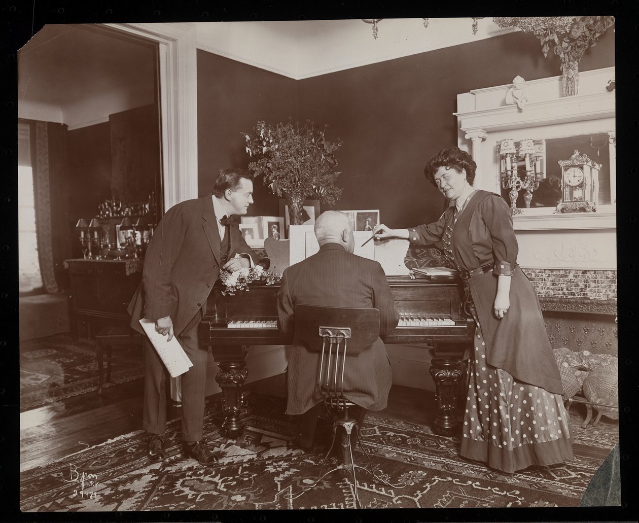 Clara De Regand apontando para uma pontuação enquanto um homem toca piano, 1910 (impressão de gelatina de prata) de Byron Company