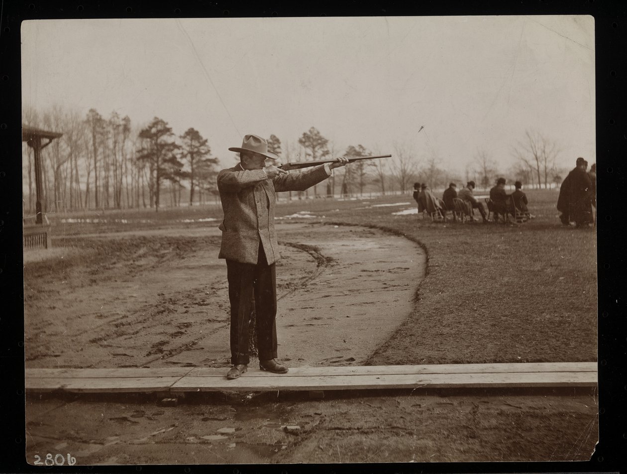 Frank trabalho apontando um rifle em um tiro de armadilha, Nova York, 1896 (impressão de gelatina de prata) de Byron Company
