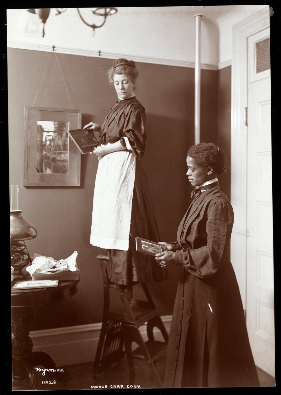 Madge Carr Cook pendurar fotos com sua empregada, c.1904 (impressão de gelatina de prata) de Byron Company