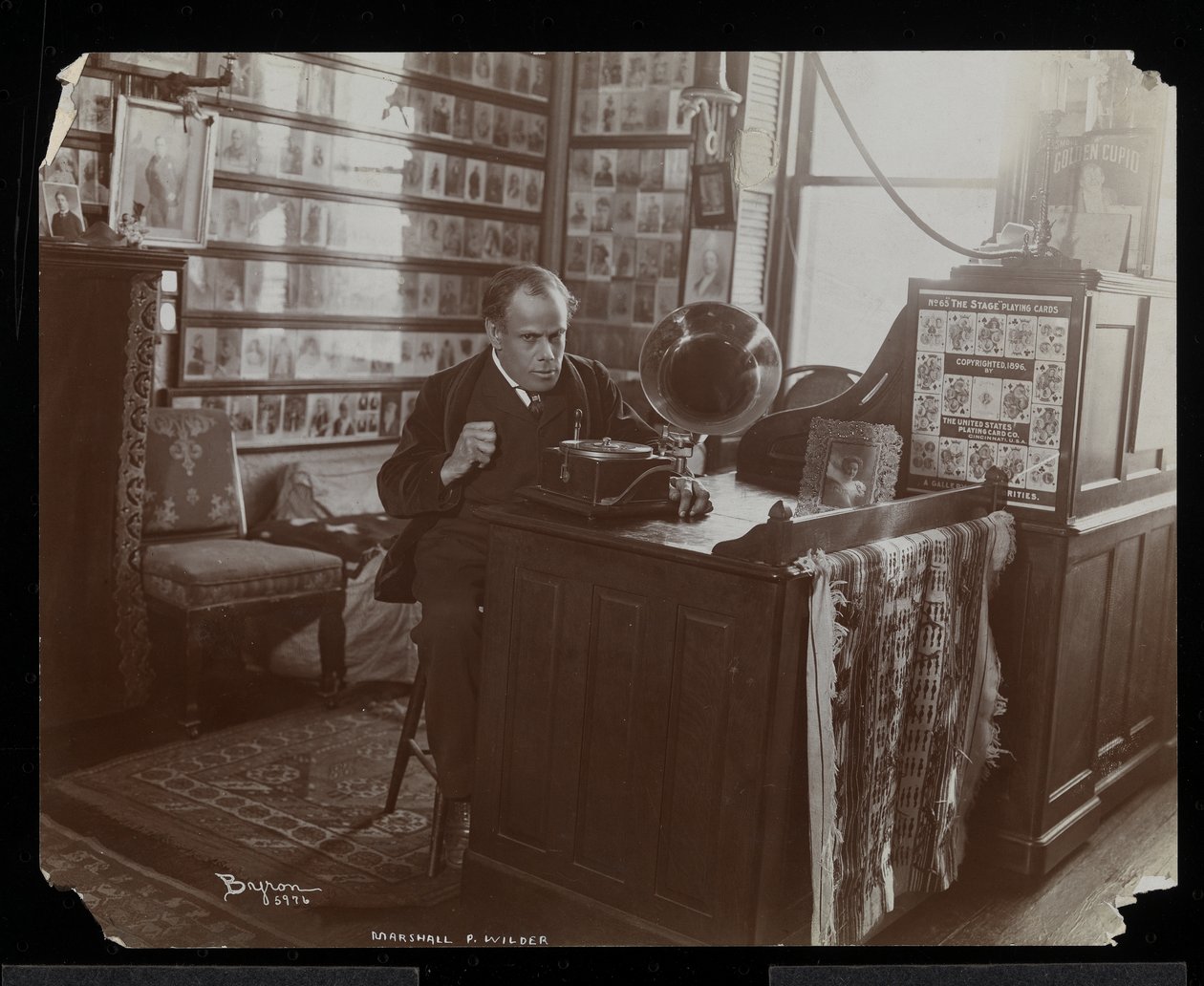 Marshall P. Wilder ouvindo um disco em uma vitrola em seu escritório, 1898-99 (impressão de gelatina de prata) de Byron Company