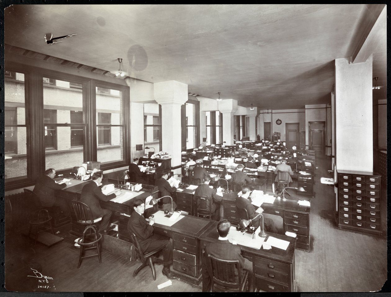 Homens e uma mulher trabalhando em mesas em um escritório da Metropolitan Life Insurance Co. na 23rd Street e Madison Avenue, Nova York, 1907 (impressão em gelatina de prata) de Byron Company