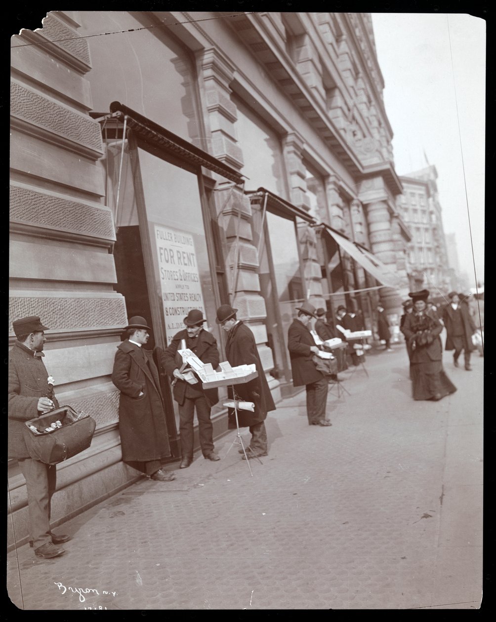 Vista de vendedores ambulantes que vendem brinquedos e outros itens em frente ao Edifício Fuller ou Flatiron na Broadway, 5th Avenue e 23rd Street, Nova York, c.1895 (impressão em gelatina de prata) de Byron Company