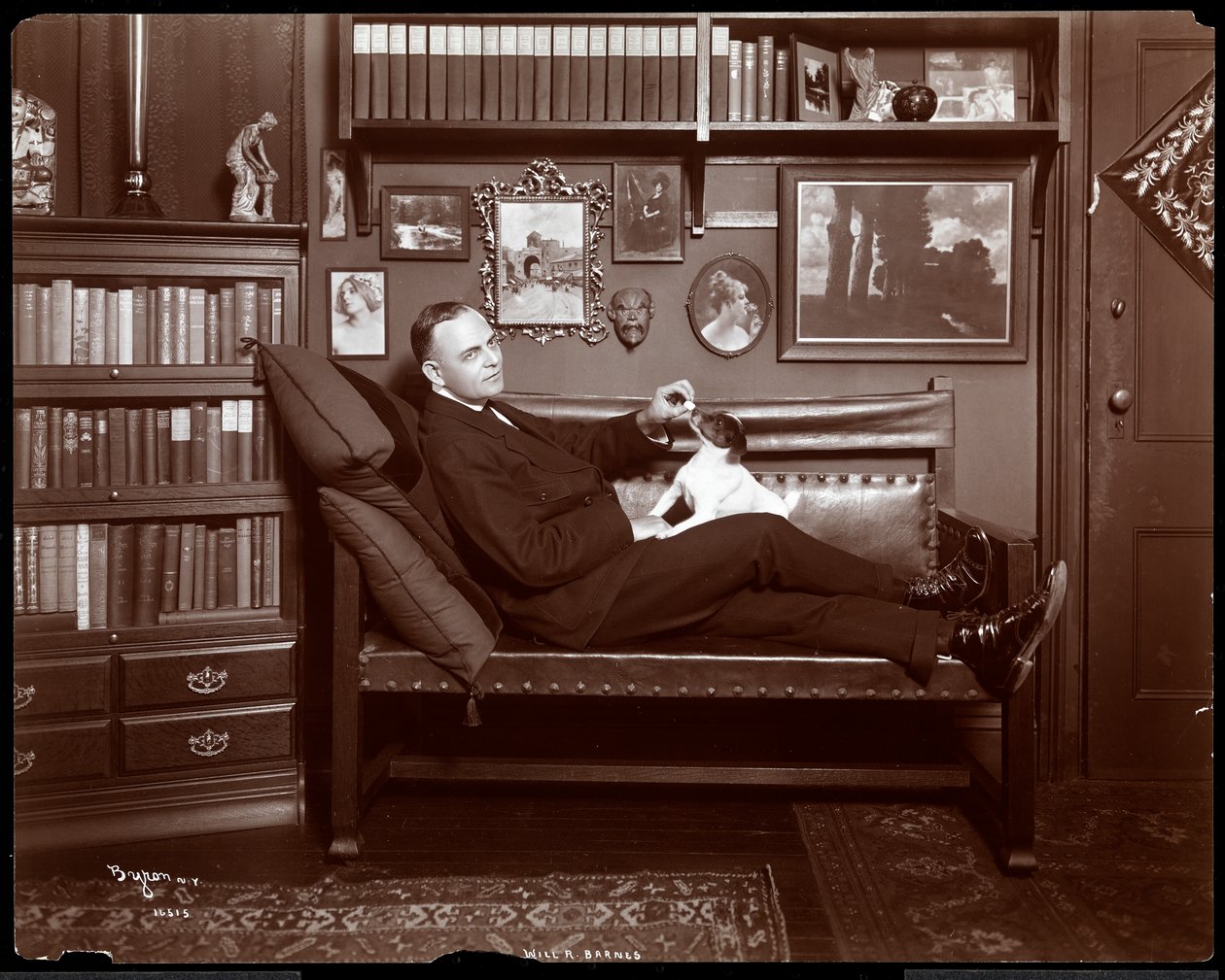 Will R. Barnes reclinou em um sofá com um cachorro em seu estúdio de biblioteca, 1903 (impressão de gelatina de prata) de Byron Company