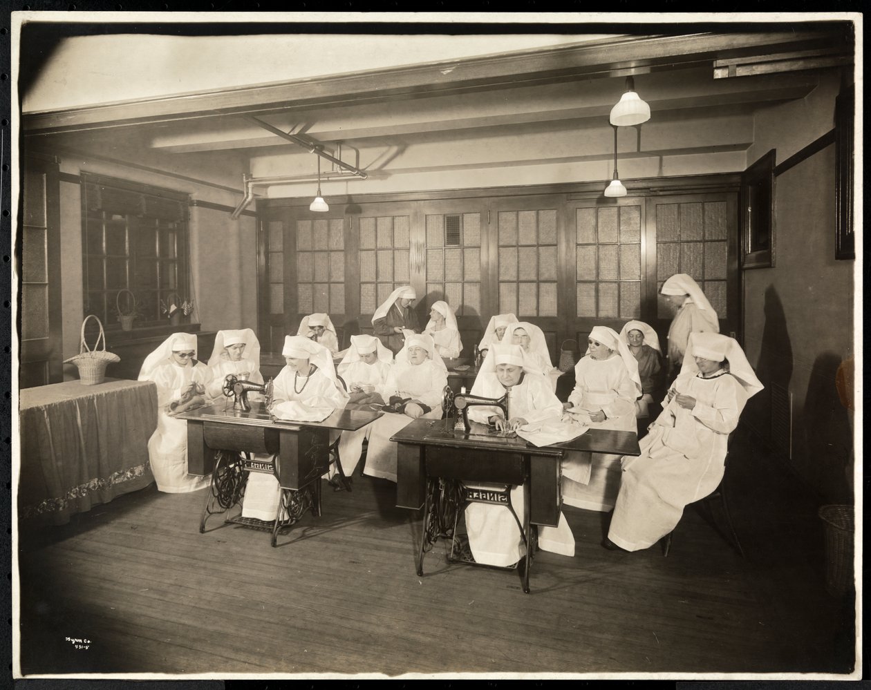 Mulheres vestindo aventais brancos, em uma aula de costura, presumivelmente durante ou associada à Primeira Guerra Mundial, Nova York, c.1920 (impressão em gelatina de prata) de Byron Company