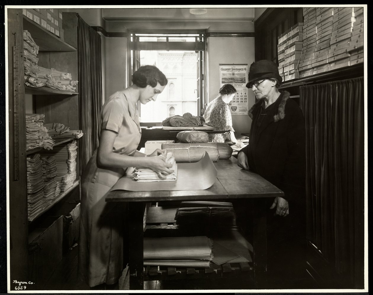 Jovem, mulher, embrulhando-se materiais de pano para um trabalhador em casa para levar com ela, na Associação de Nova York para os cegos, 111 East 59th Street, Nova York, 1931 (impressão de gelatina de prata) de Byron Company