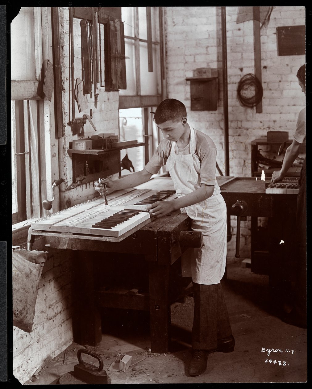Um jovem que trabalha na fábrica Harrington Piano Co., 1907 (impressão em gelatina prateada) de Byron Company