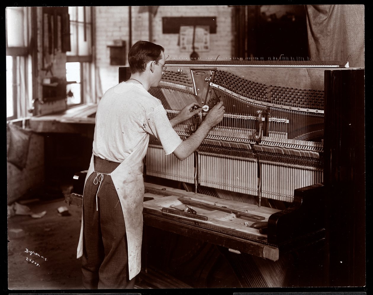 Homem trabalhando na Hardman, Peck und Co. fábrica de piano, Nova York, 1907 (impressão de gelatina de prata) de Byron Company
