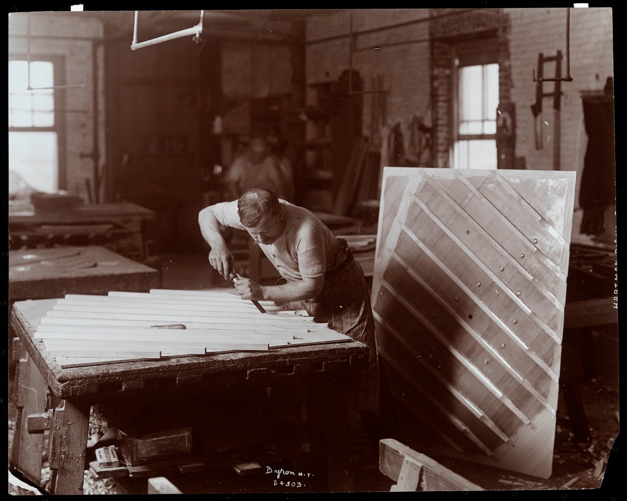 Homem trabalhando na Hardman, Peck und Co. fábrica de piano, Nova York, 1907 (impressão de gelatina de prata) de Byron Company