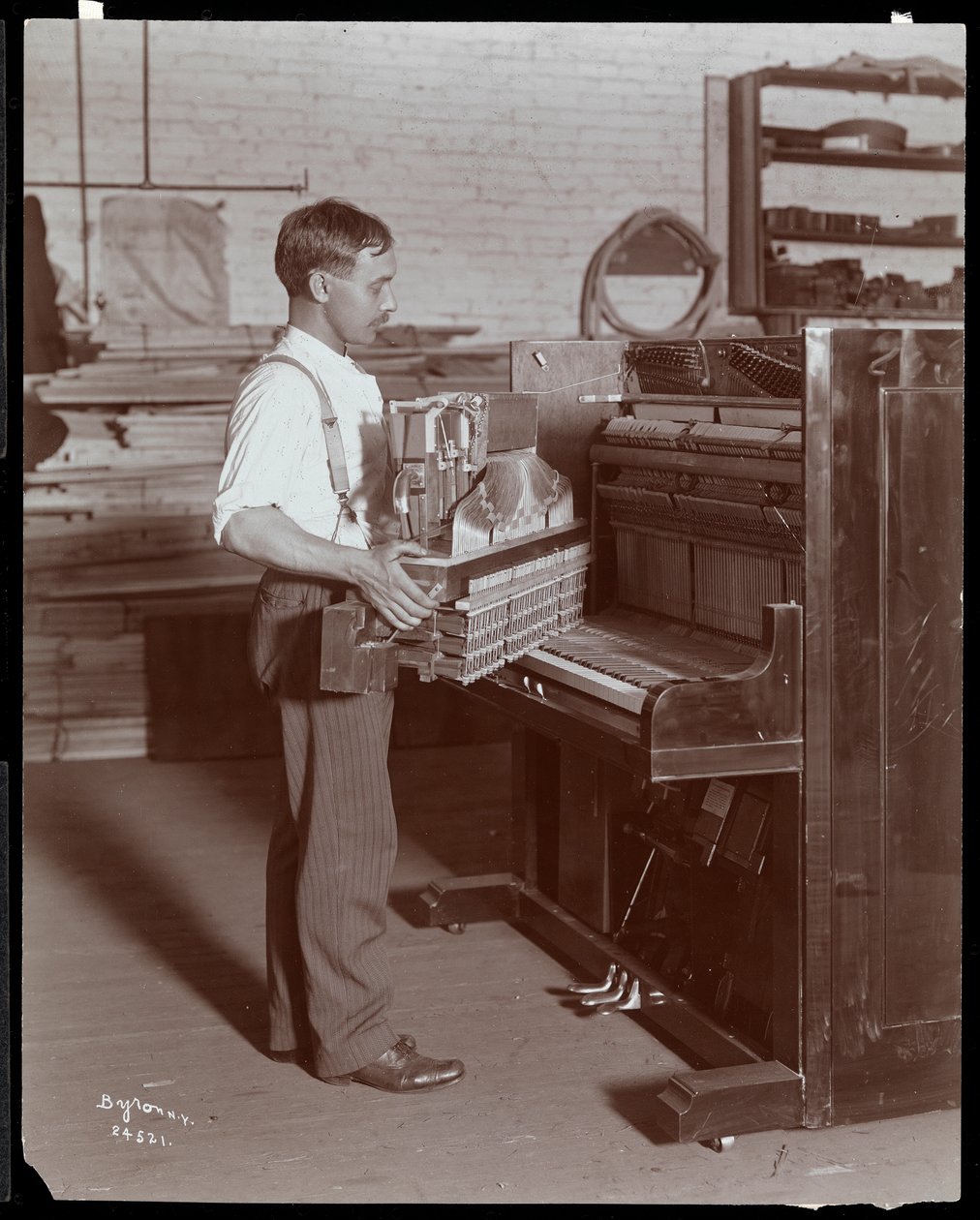 Homem trabalhando na Hardman, Peck und Co. fábrica de piano, Nova York, 1907 (impressão de gelatina de prata) de Byron Company