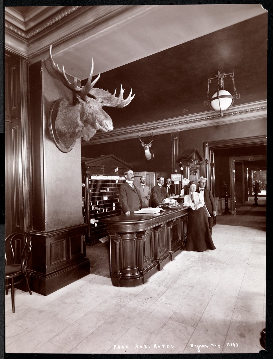 O lobby e o balcão de registo no Park Avenue Hotel, 1901 ou 1902 (impressão em gelatina prateada) de Byron Company