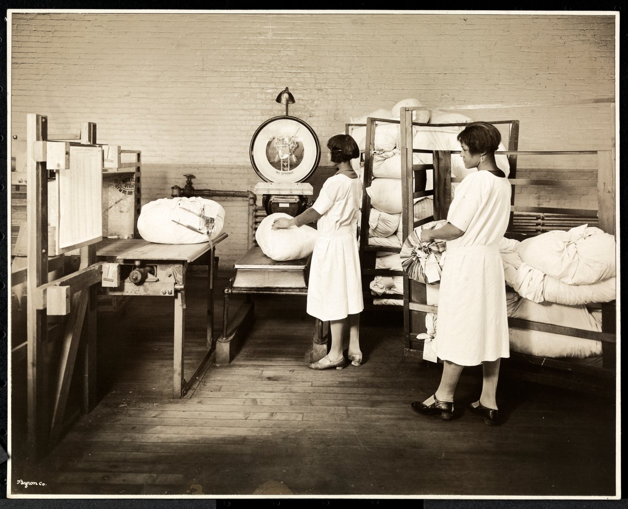 Duas mulheres afro-americanas pesando sacos de roupa na lavanderia Carolyn em 111 East 128th Street, East Harlem, Nova York, 1928 (impressão de gelatina de prata) de Byron Company