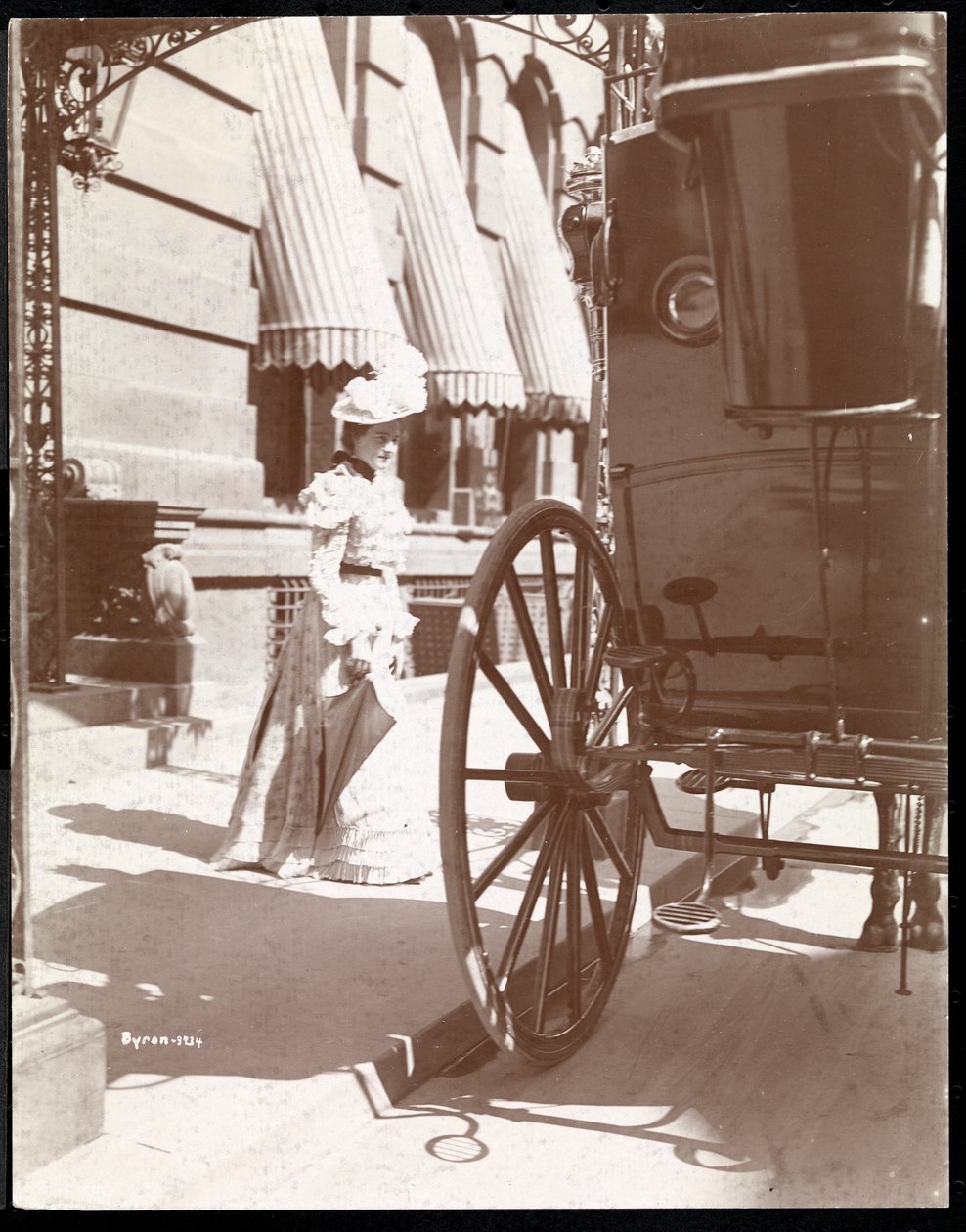 Mulher se aproxima de uma carruagem no Hotel Waldorf Astoria, 34th Street e 5th Avenue, Nova York, 1897 ou 1898 (impressão de gelatina de prata) de Byron Company