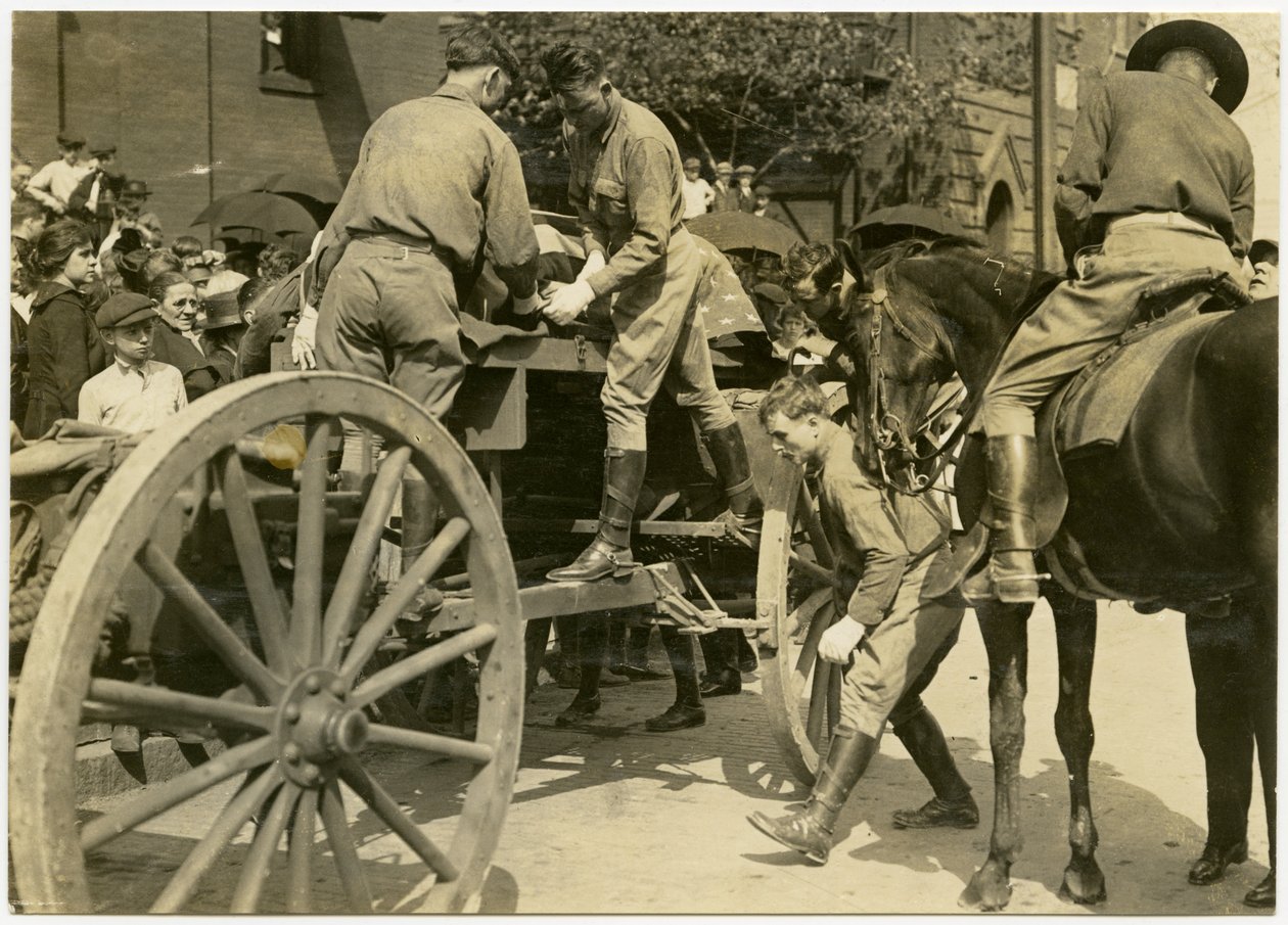Fotografia horizontal em sépia mostrando homens uniformizados descarregando um objeto envolto na bandeira americana, possivelmente um caixão, de um vagão aberto. Uma multidão de pessoas olha da calçada de Carl Michel