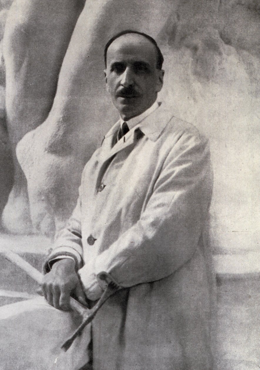 Retrato de três quartos do escultor Edoardo Rubino com martelina na mão. No fundo, um esboço pode ser feito de Carlo Gherlone
