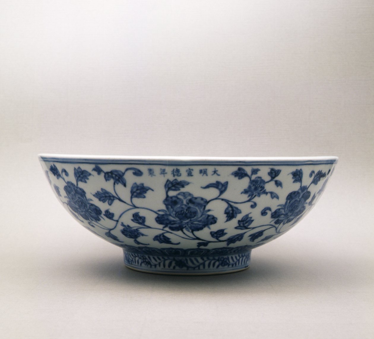Bacia azul e branca com a decoração floral que carrega a marca do reino de Hsuan Te, 1426-35, dinastia de Ming, 1368-1644 (porcelana) de Chinese School